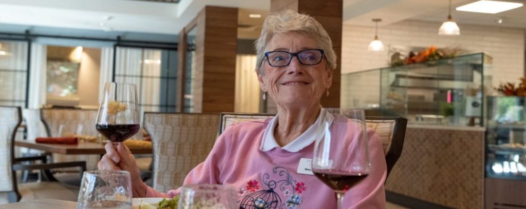 Clermont Park resident enjoying meal and wine in The Pines Cafe