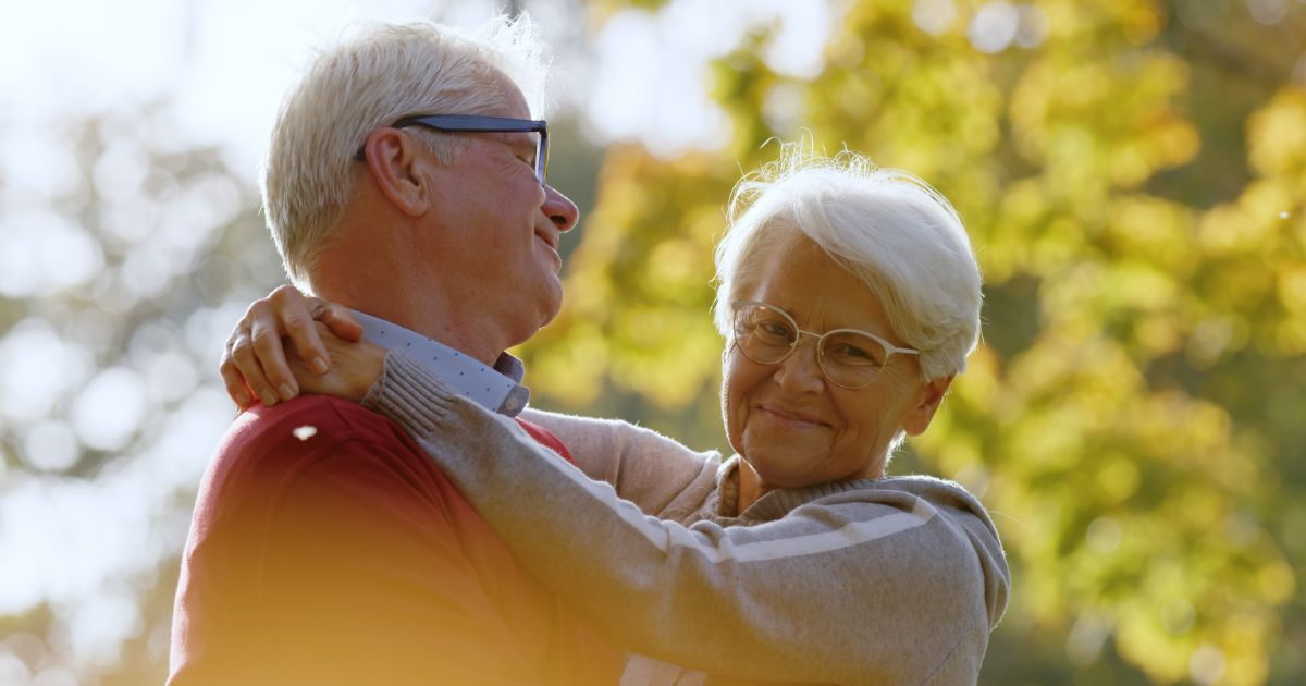 Older couple smiling and hugging outdoors