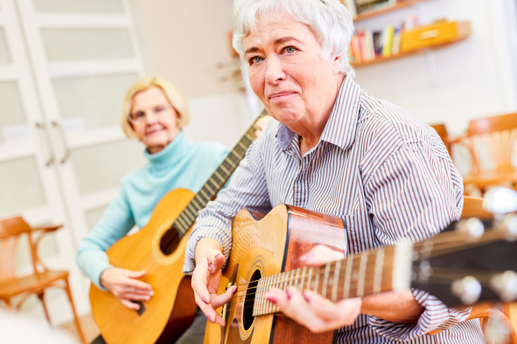 two senior women playing guitars